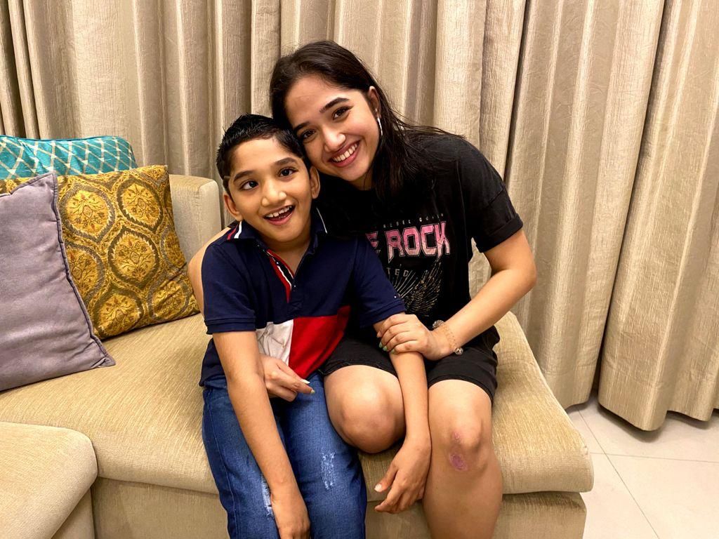 Aadya and Aadi laughing together on a sofa.