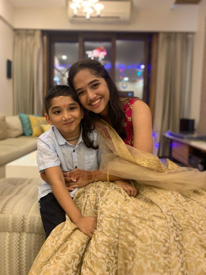 Aadya in festive clothes sitting with Aadi at home.